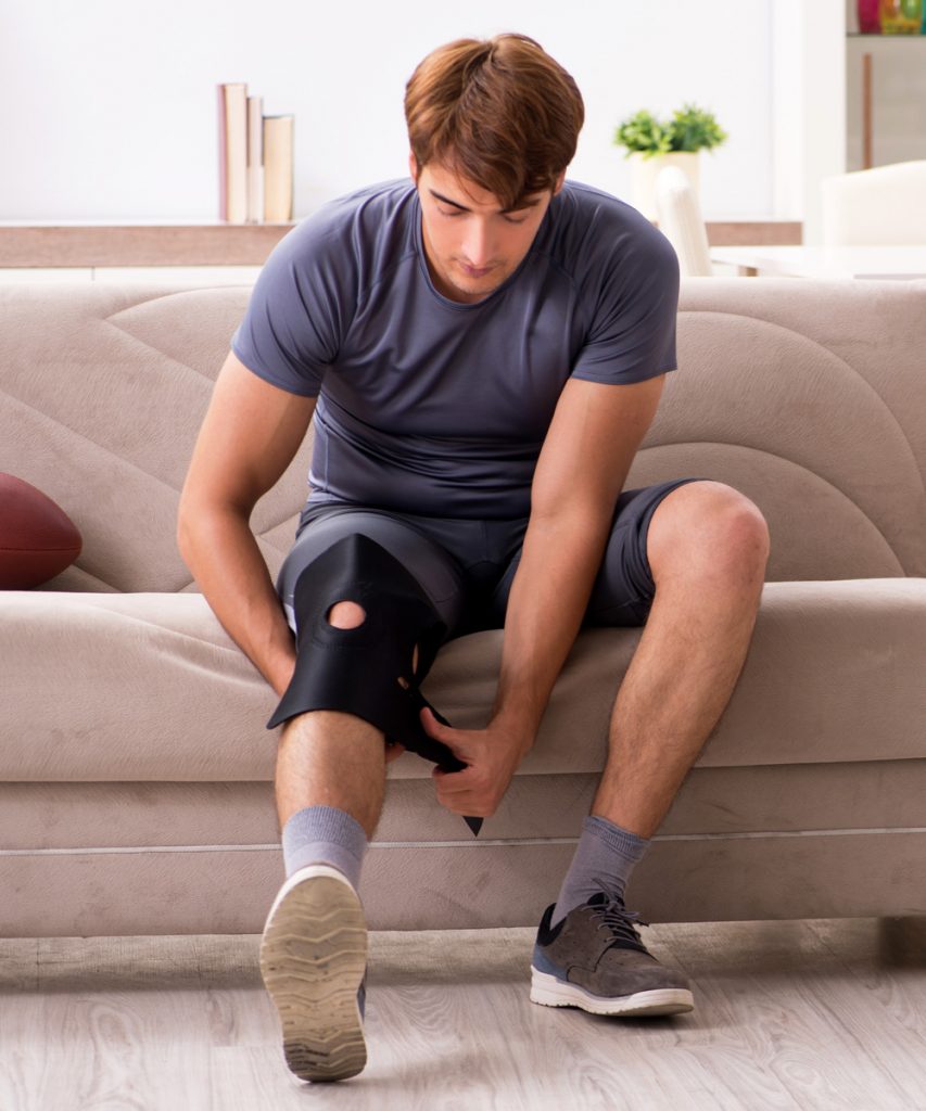 Man putting on a knee brace after sports injuries