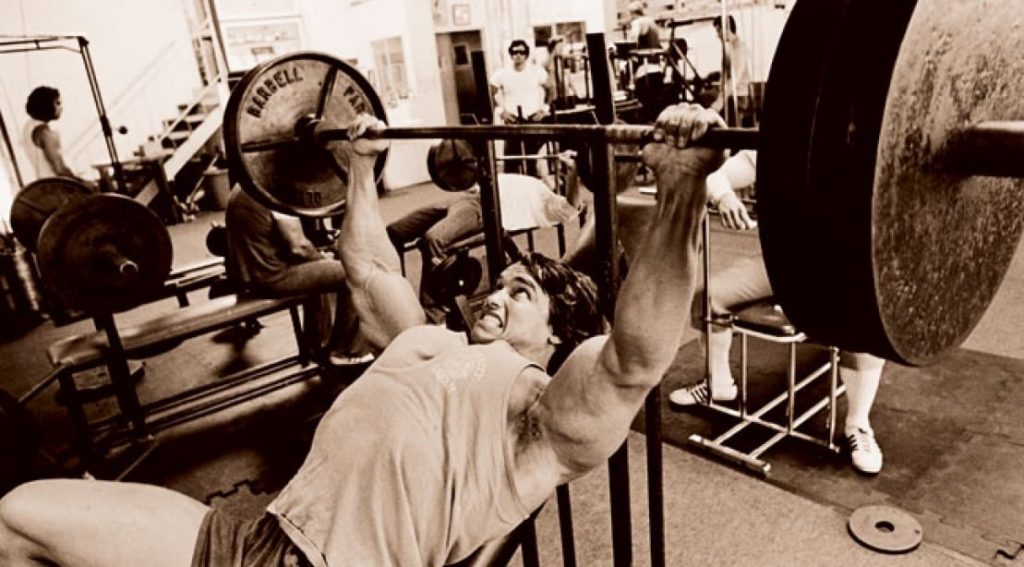A young Arnold Schwarzenegger lifting weights