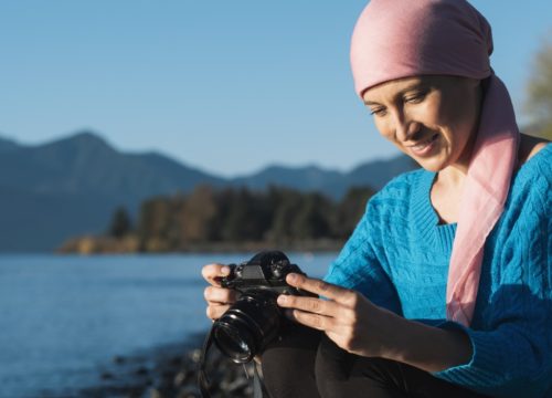 Cancer survivor holding a camera near a river